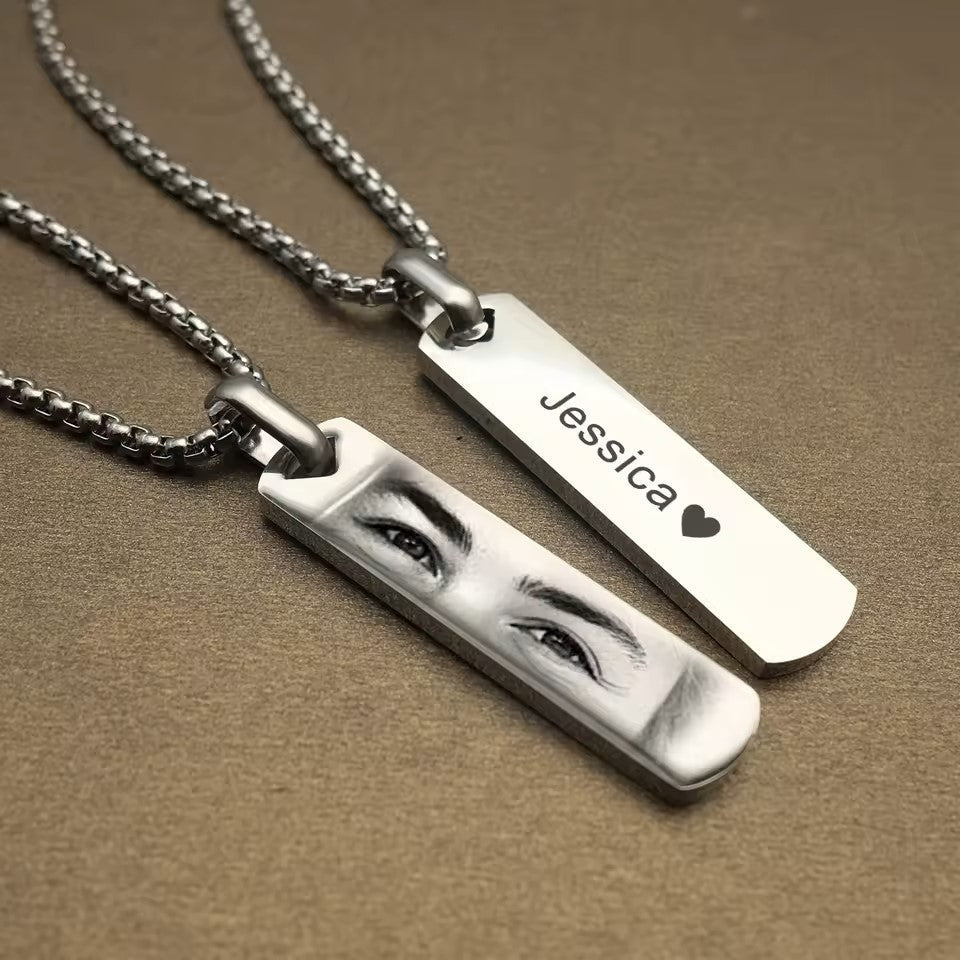 Two silver necklaces with engraved names on a brown background